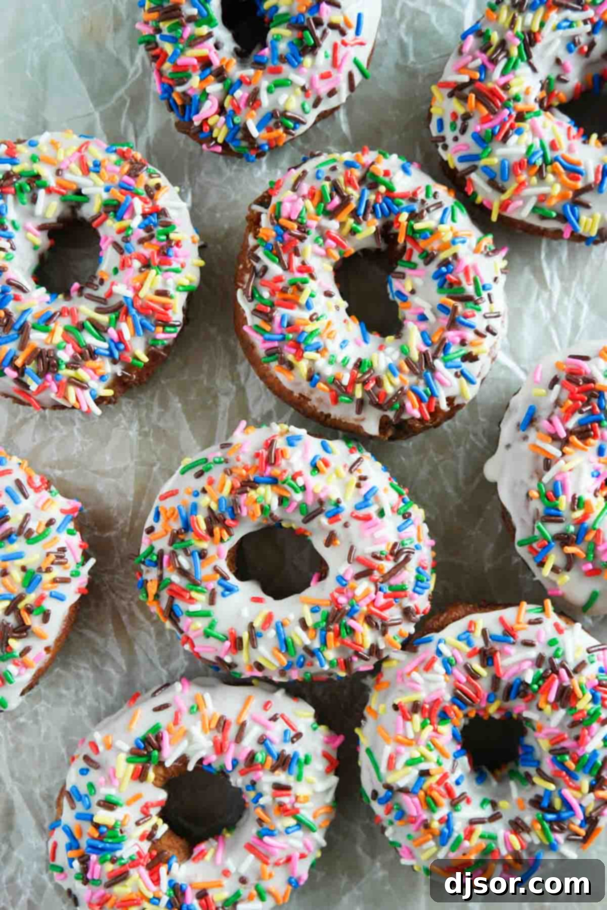 Freshly fried Funfetti Donuts cooling on parchment paper.