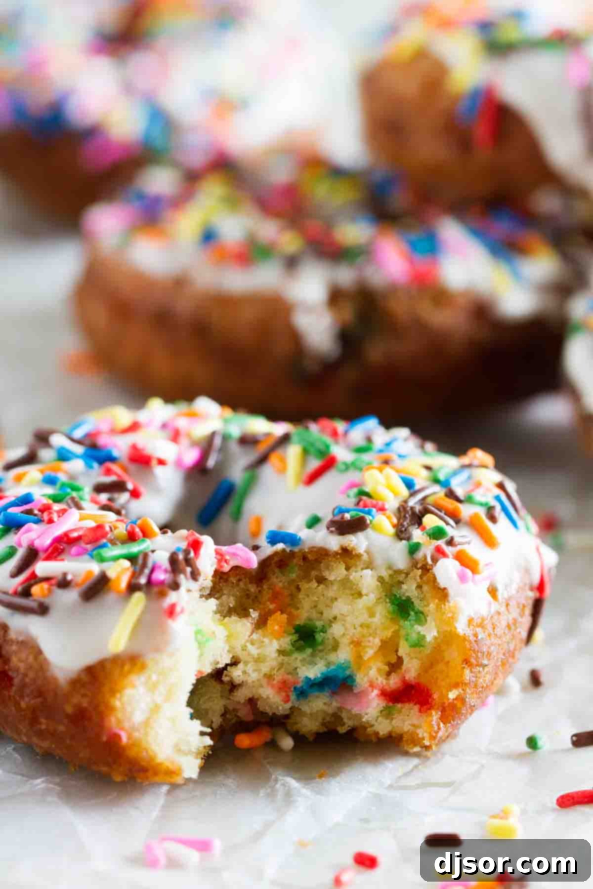 A Funfetti donut with a bite taken, showcasing its moist interior and sprinkles.