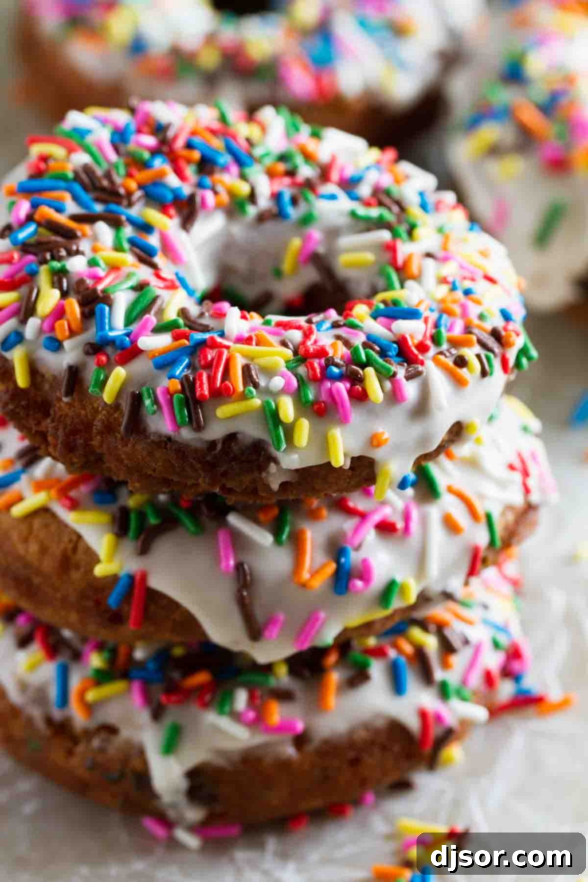 A stack of three Homemade Funfetti Donuts with colorful sprinkles and a sweet glaze.