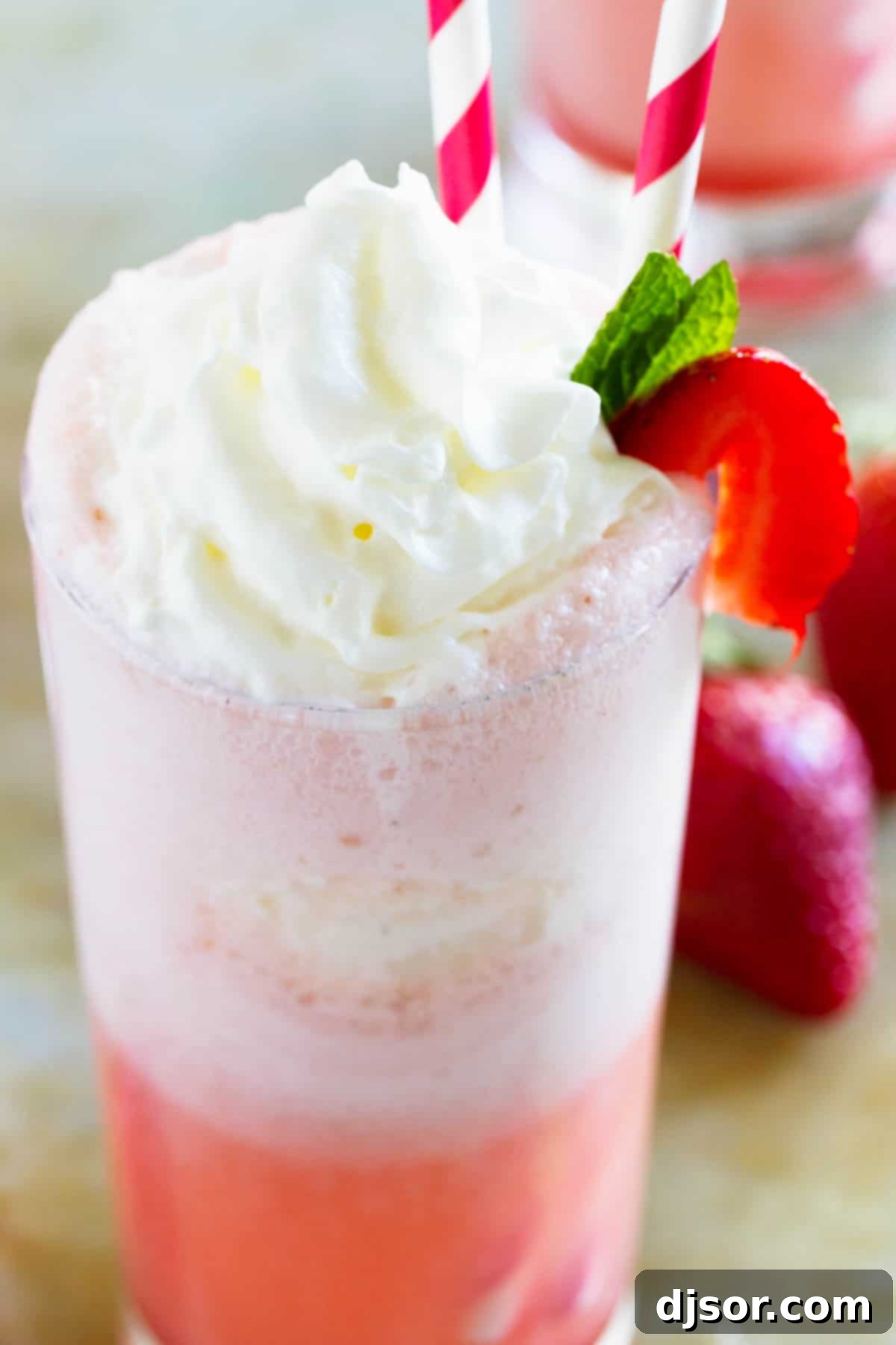 Close-up shot of a Strawberry Cream Float in a tall glass, adorned with a swirl of whipped cream and a fresh strawberry.