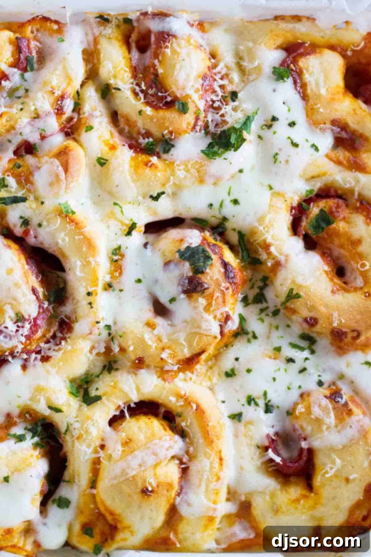 Golden-brown pizza rolls topped with melted cheese and fresh green herbs, possibly basil.