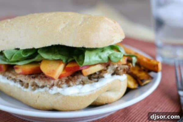 Golden Georgia Peach Chicken Sandwich 2 A delicious Georgia Peach Chicken Sandwich served with a side of crispy sweet potato fries, highlighting the fresh peach slices and jalapenos.