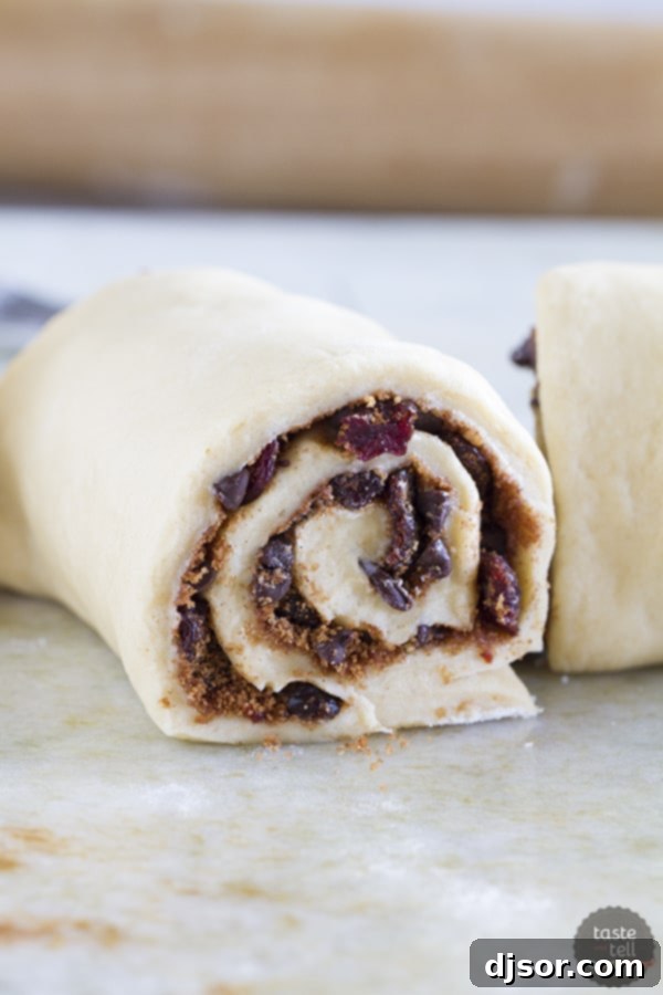 Rolling up the dough filled with cherries, chocolate, and cinnamon for streusel rolls.