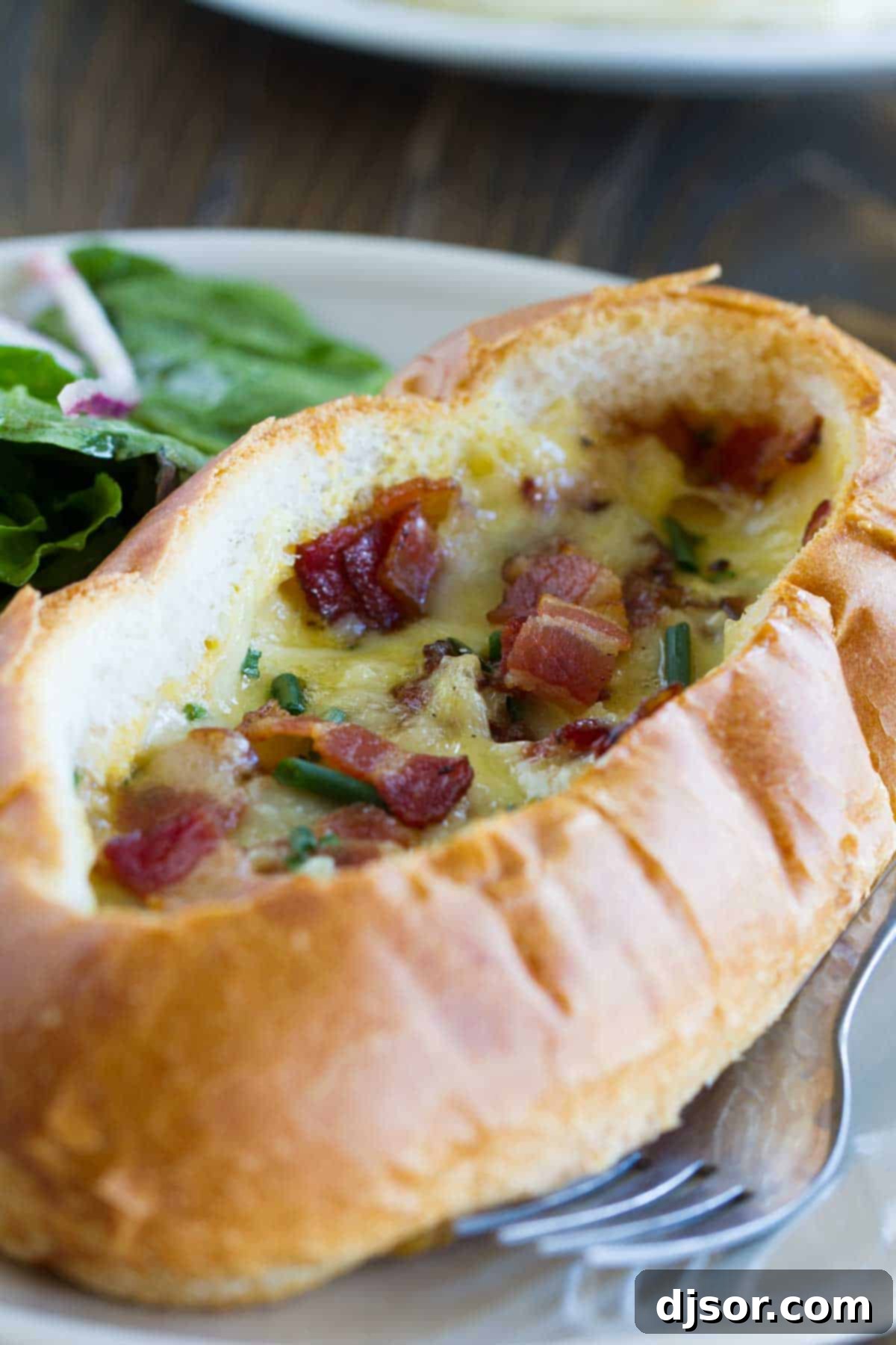 Ultimate Breakfast Bread Boats 2 Baked Egg, Bacon, and Cheese Boat topped with more bacon and chives, ready to be served for a delicious breakfast or brunch.