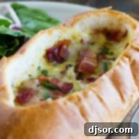 Ultimate Breakfast Bread Boats 5 Baked Egg, Bacon, and Cheese Boat topped with more bacon and chives, serving as the main image for the recipe card.