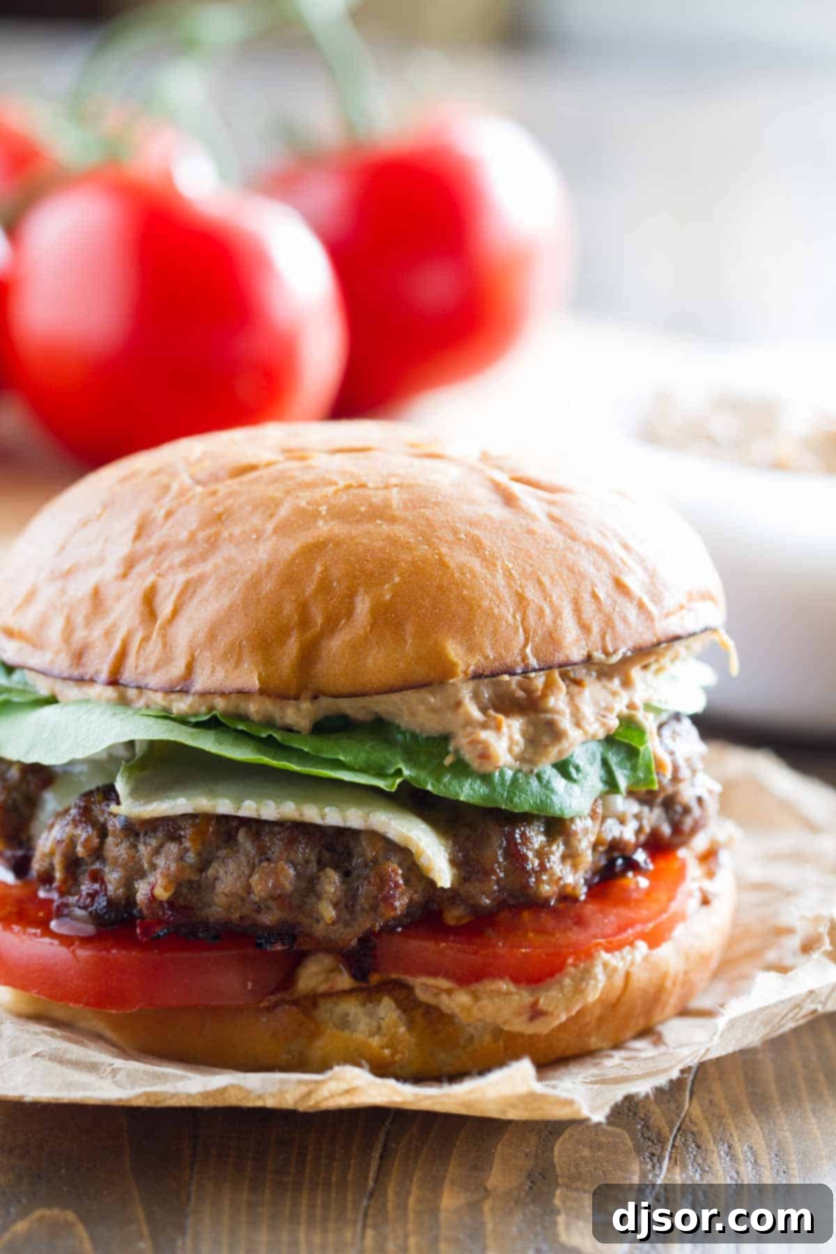 Creamy Brie Burger with Zesty Sun-Dried Tomato and Artichoke Spread 2 A stacked Brie Burger with Sun-Dried Tomato and Artichoke Spread, fresh lettuce, and ripe tomatoes, ready to be enjoyed.