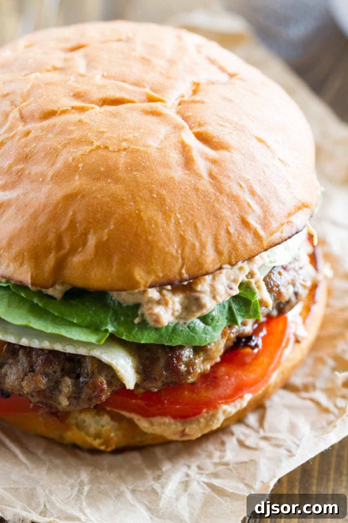 Creamy Brie Burger with Zesty Sun-Dried Tomato and Artichoke Spread 4 A close-up view of a gourmet Brie Burger, showcasing the melted brie cheese and the generous layers of sun-dried tomato and artichoke spread, with fresh lettuce and tomatoes peeking out.