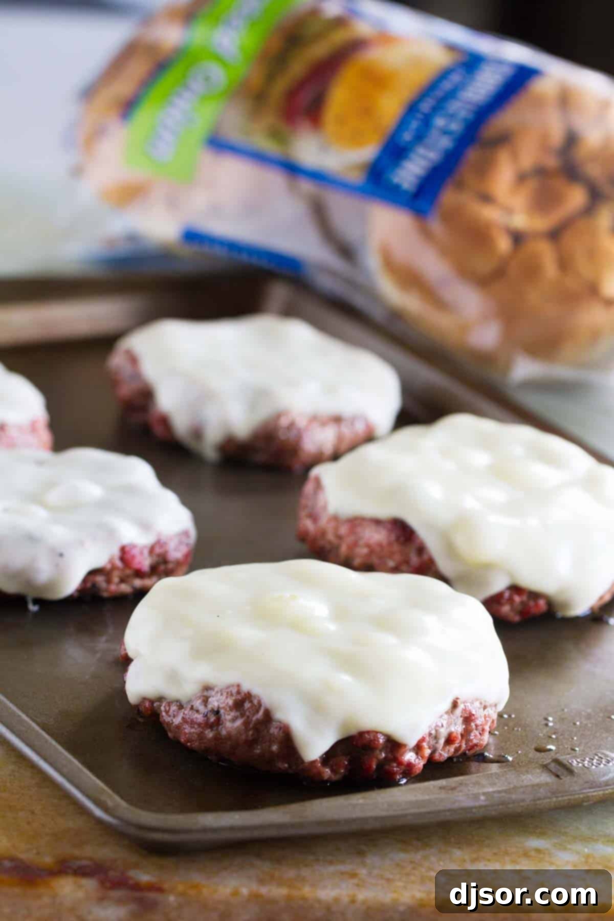 Triple Threat Pork Burger 4 Burger patties with cheese on a baking sheet.