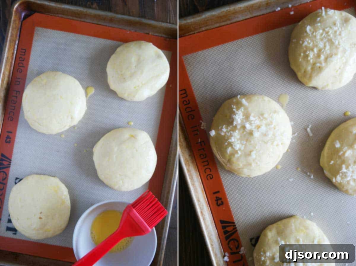 Fluffy Garlic Parmesan Brioche Buns 6 Garlic Parmesan Brioche Buns dough rising on a baking sheet, brushed with egg wash and topped with shaved Parmesan before baking.