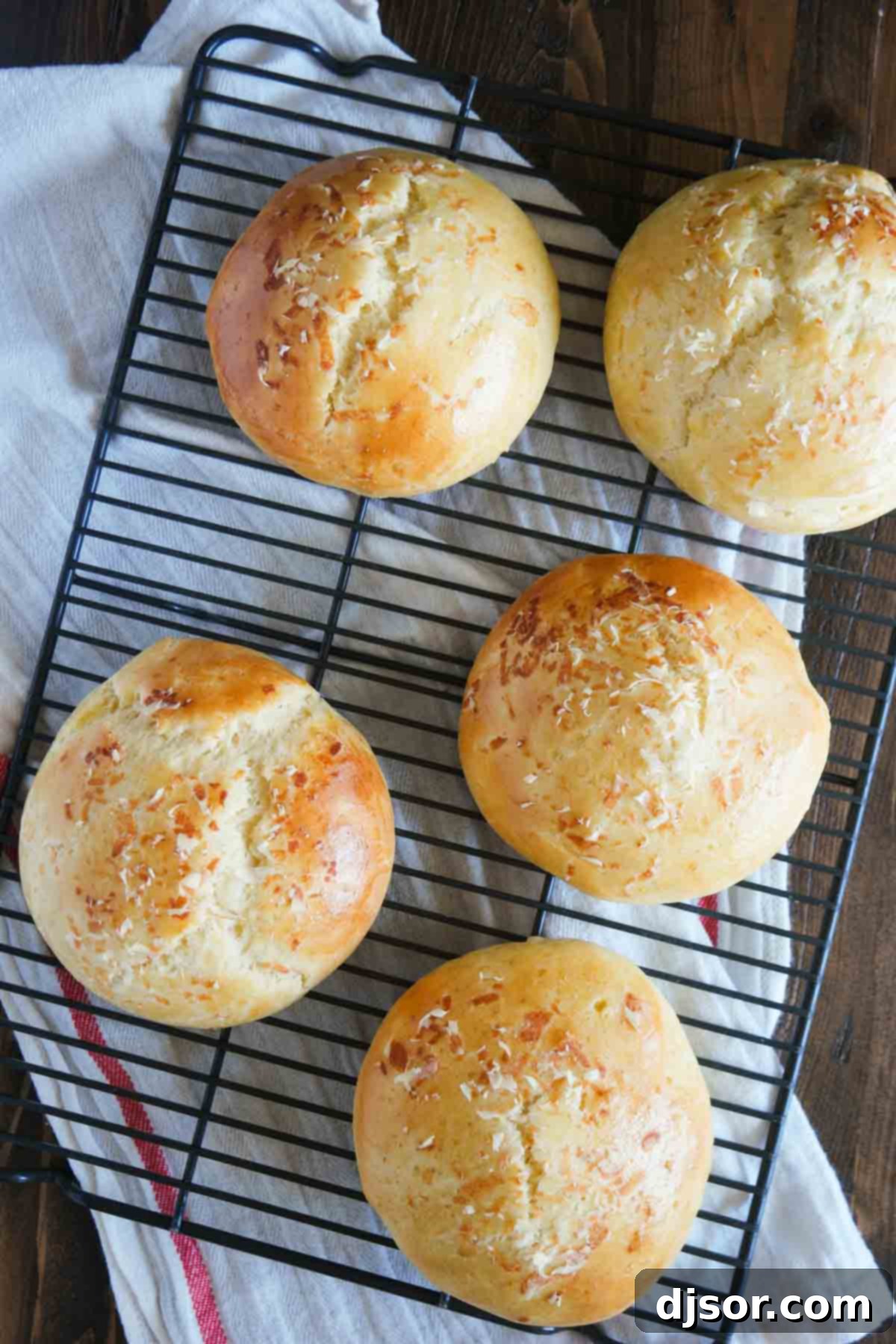 Fluffy Garlic Parmesan Brioche Buns 7 Freshly baked Garlic Parmesan Brioche Buns cooling on a wire rack after removal from the oven.