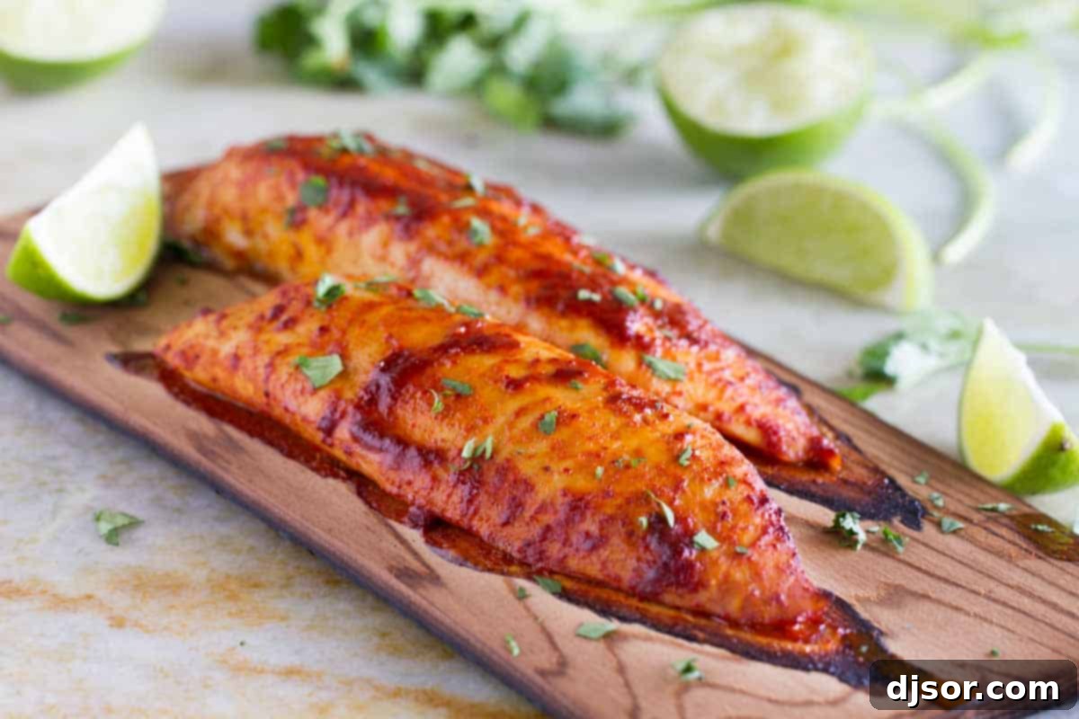 Two perfectly grilled fish fillets on a cedar plank, garnished with fresh lime wedges, ready to serve.