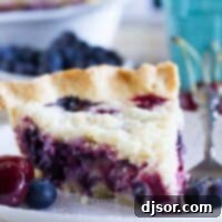 Slice of cherry and blueberry cream pie on a plate.
