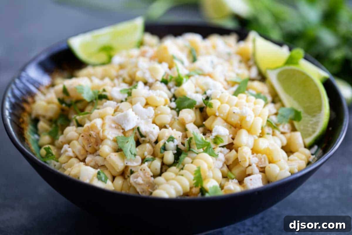 Take advantage of sweet summer corn with this Mexican Corn Salad - filled with Mexican cheese, lime, cilantro and a zing of spiciness. A vibrant bowl of Mexican Corn Salad garnished with fresh lime wedges and cilantro sprigs, ready to serve.