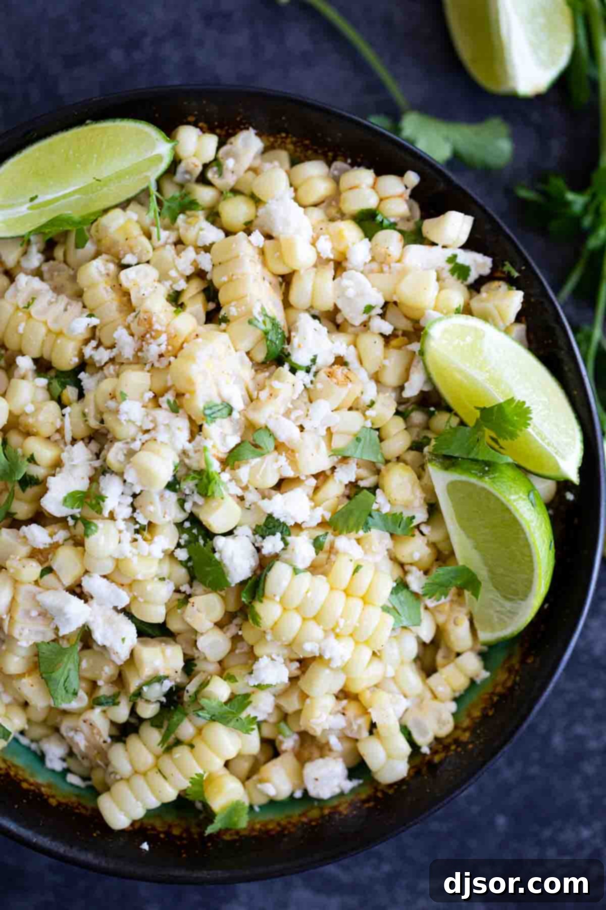 Take advantage of sweet summer corn with this Mexican Corn Salad - filled with Mexican cheese, lime, cilantro and a zing of spiciness. Overhead shot of a bowl of freshly prepared Mexican Corn Salad, garnished with lime and cilantro, showing its colorful ingredients.