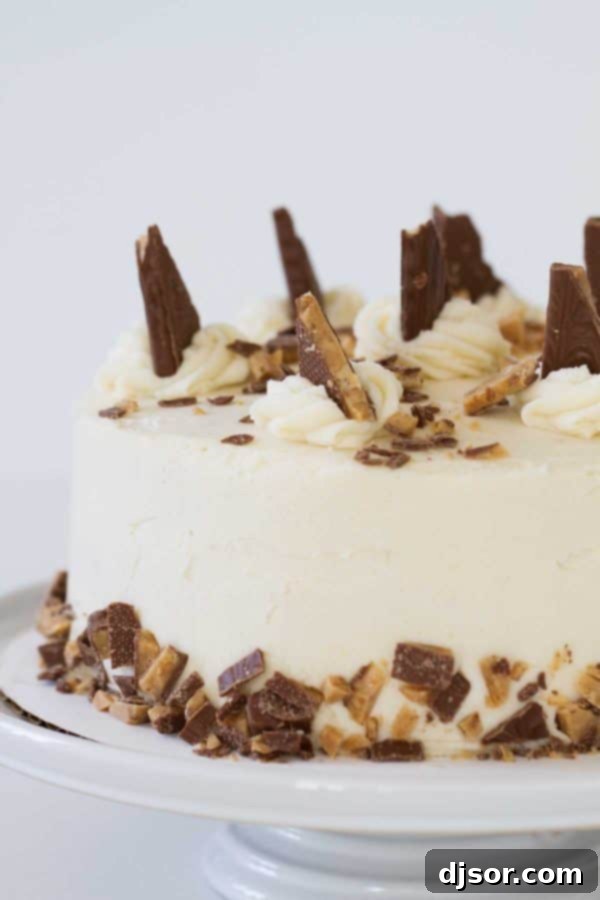 Deep Caramel Candy Bar Indulgence 2 Tall, moist layers of Burnt Sugar Candy Bar Cake, frosted with browned butter cream cheese frosting and generously topped with chopped Heath candy bars, sitting on a white cake stand.