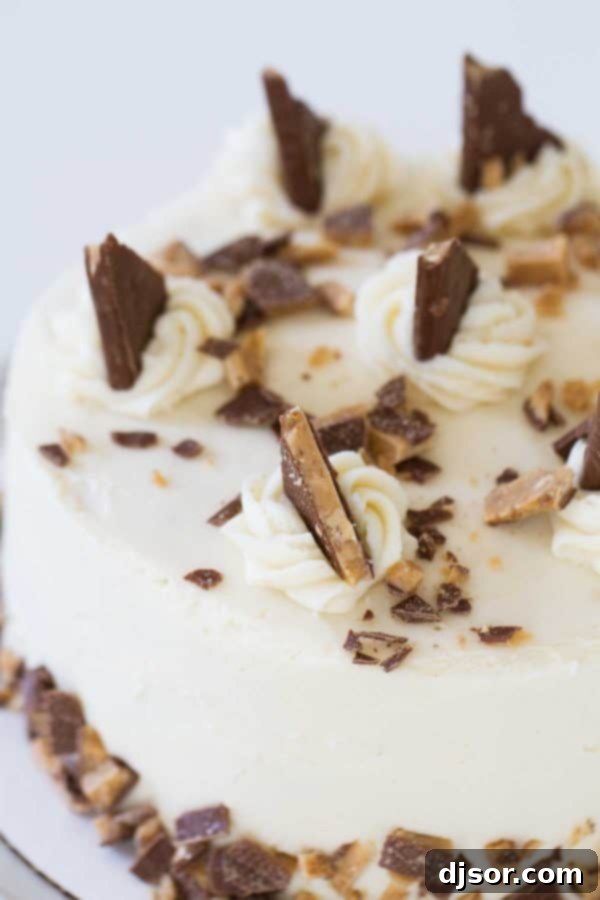 Deep Caramel Candy Bar Indulgence 3 A close-up of a slice of Burnt Sugar Candy Bar Cake, showing the moist caramel-colored layers, thick cream cheese frosting, and visible pieces of Heath candy bars embedded in the frosting.