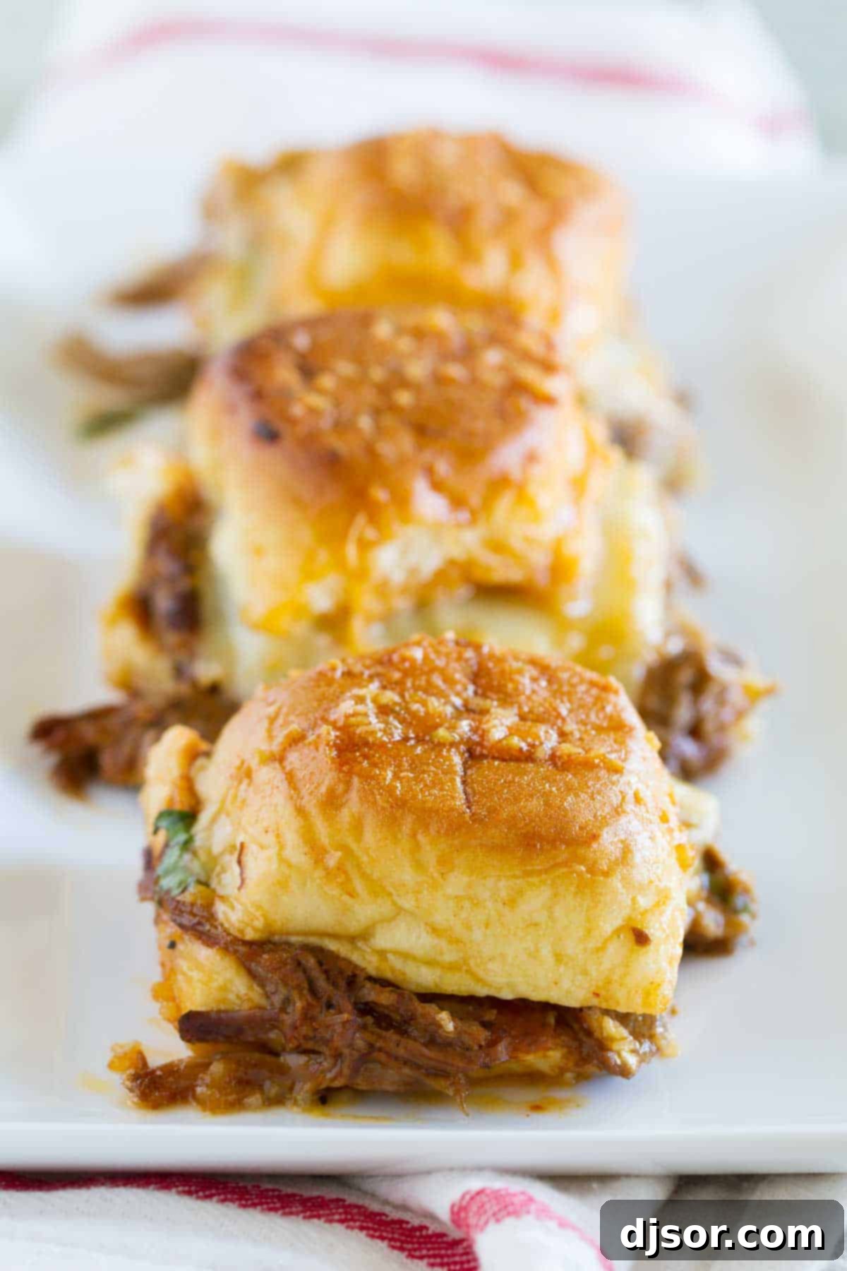 Three Enchilada Beef Sliders arranged on a serving platter, showing their tempting layers.