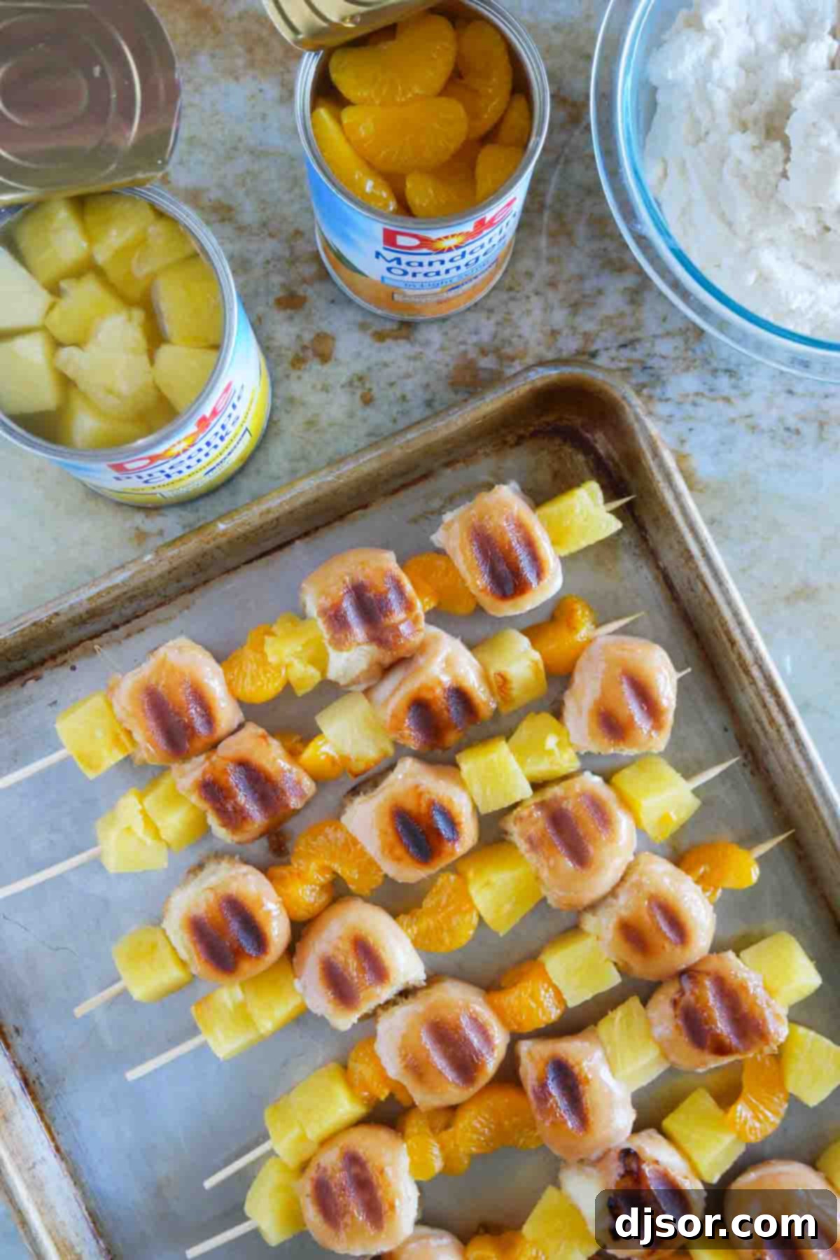 Grilled Donut Kabobs with Pineapple and Oranges Grilled Donut Kabobs, featuring perfectly toasted donut holes interspersed with caramelized pineapple chunks and mandarin oranges, arranged artfully on a platter.
