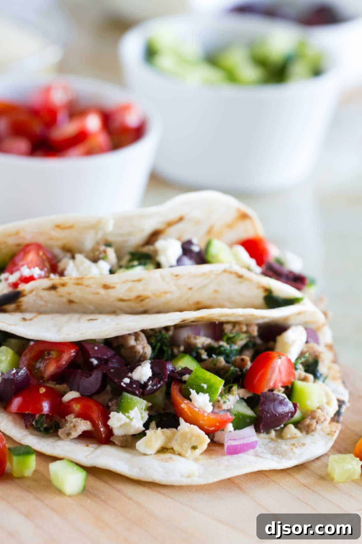 Souvlaki Shells 2 Vibrant Greek Tacos served on warm flour tortillas, generously filled with seasoned ground turkey, spinach, creamy hummus, and topped with fresh cucumber, tomatoes, red onion, kalamata olives, and crumbled feta cheese.