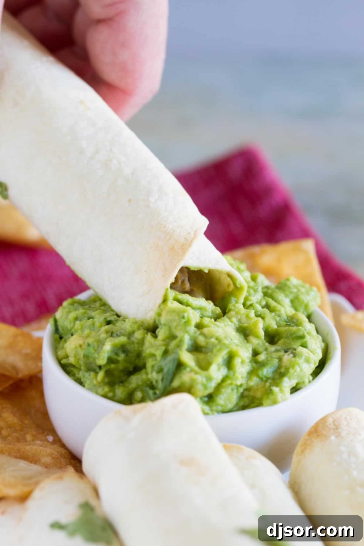 Crispy Baked Shredded Beef Taquitos 3 A golden brown Mexican Shredded Beef Baked Taquito being dipped into a luscious bowl of creamy homemade guacamole.