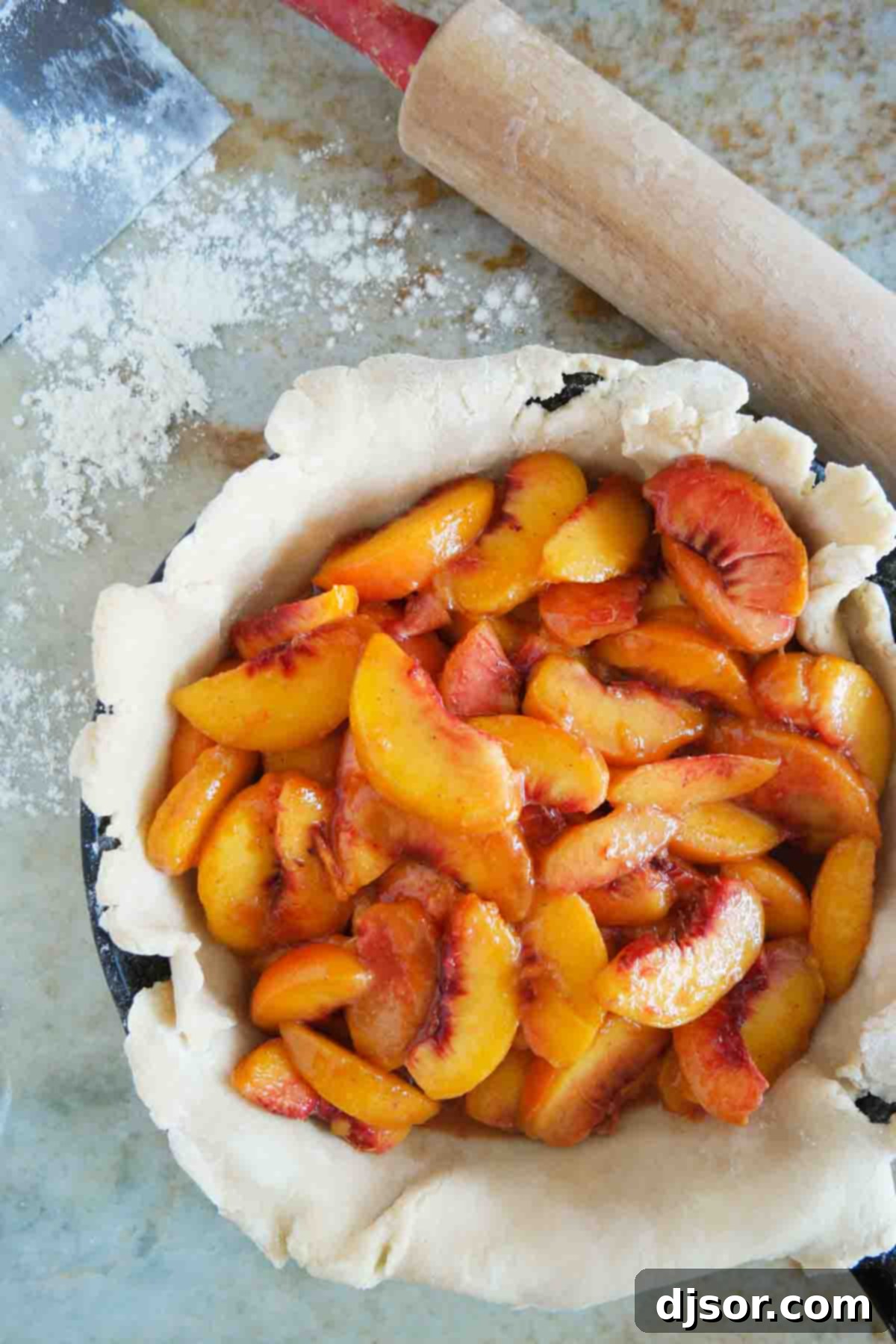 Close-up of a pie crust generously filled with vibrant, sliced fresh peaches, ready for baking.