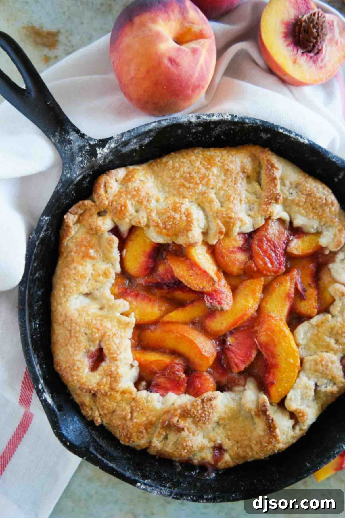 A fully baked Cast Iron Peach Crostata, golden and bubbling, resting in its cast iron skillet.
