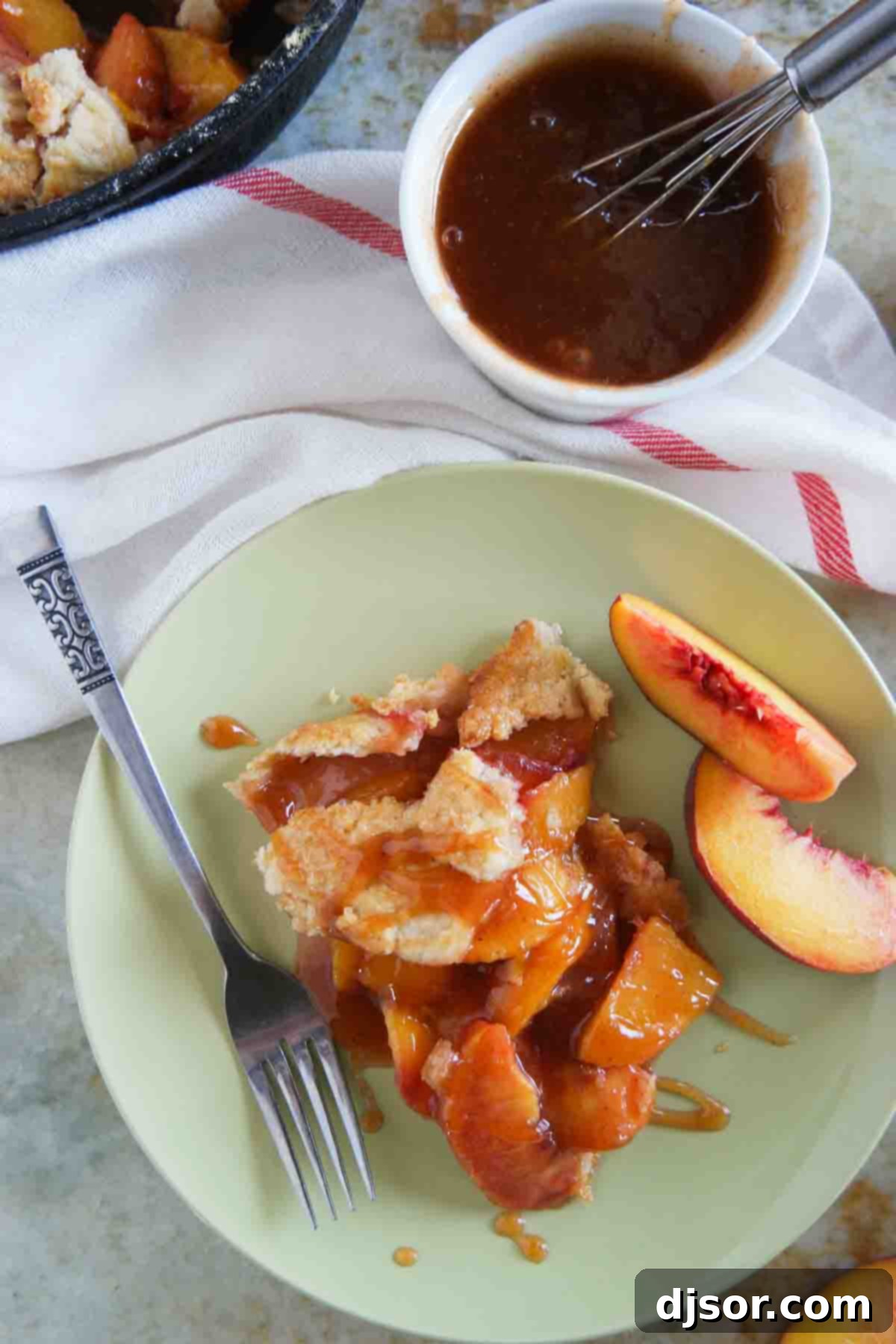 A delectable slice of Cast Iron Peach Crostata, topped with the rich, reduced peach sauce, served hot.
