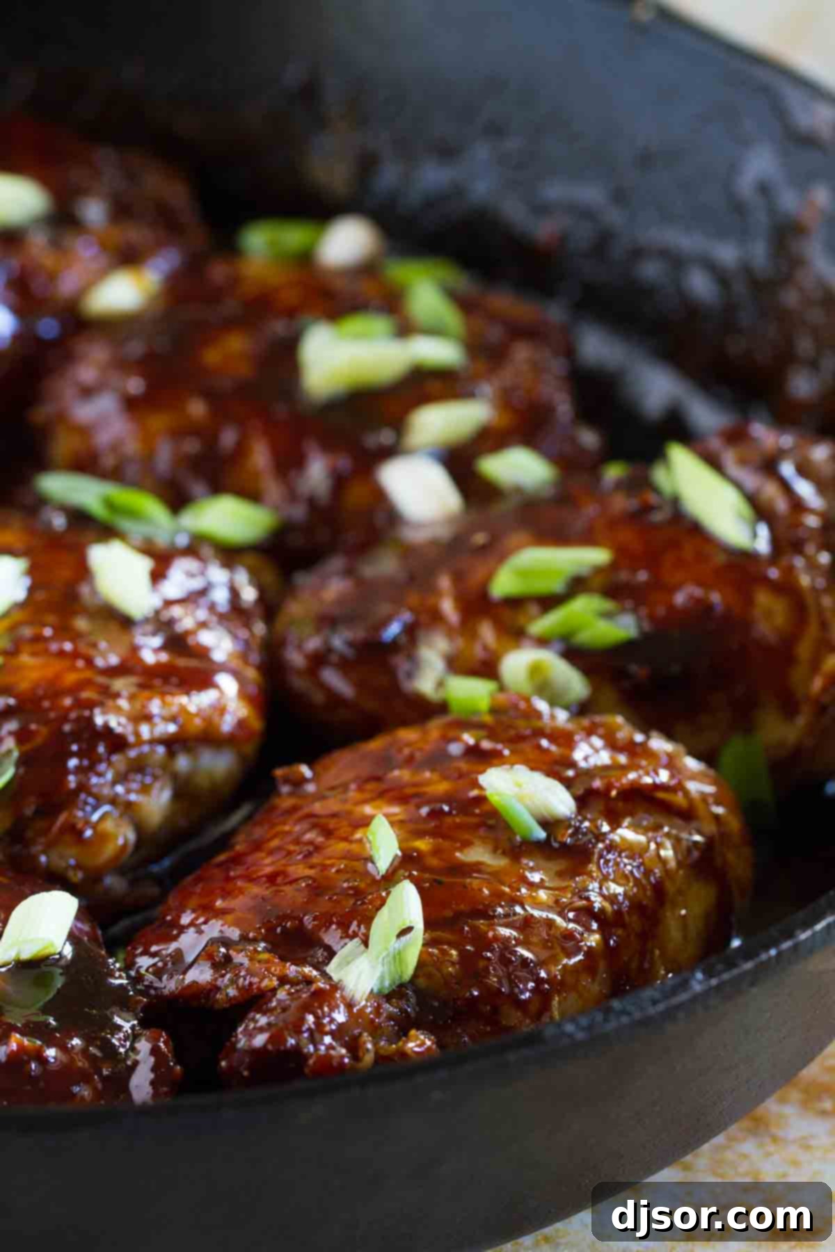 Glazed Cast Iron Teriyaki Chicken Thighs with perfectly crispy skin, garnished with fresh green onions