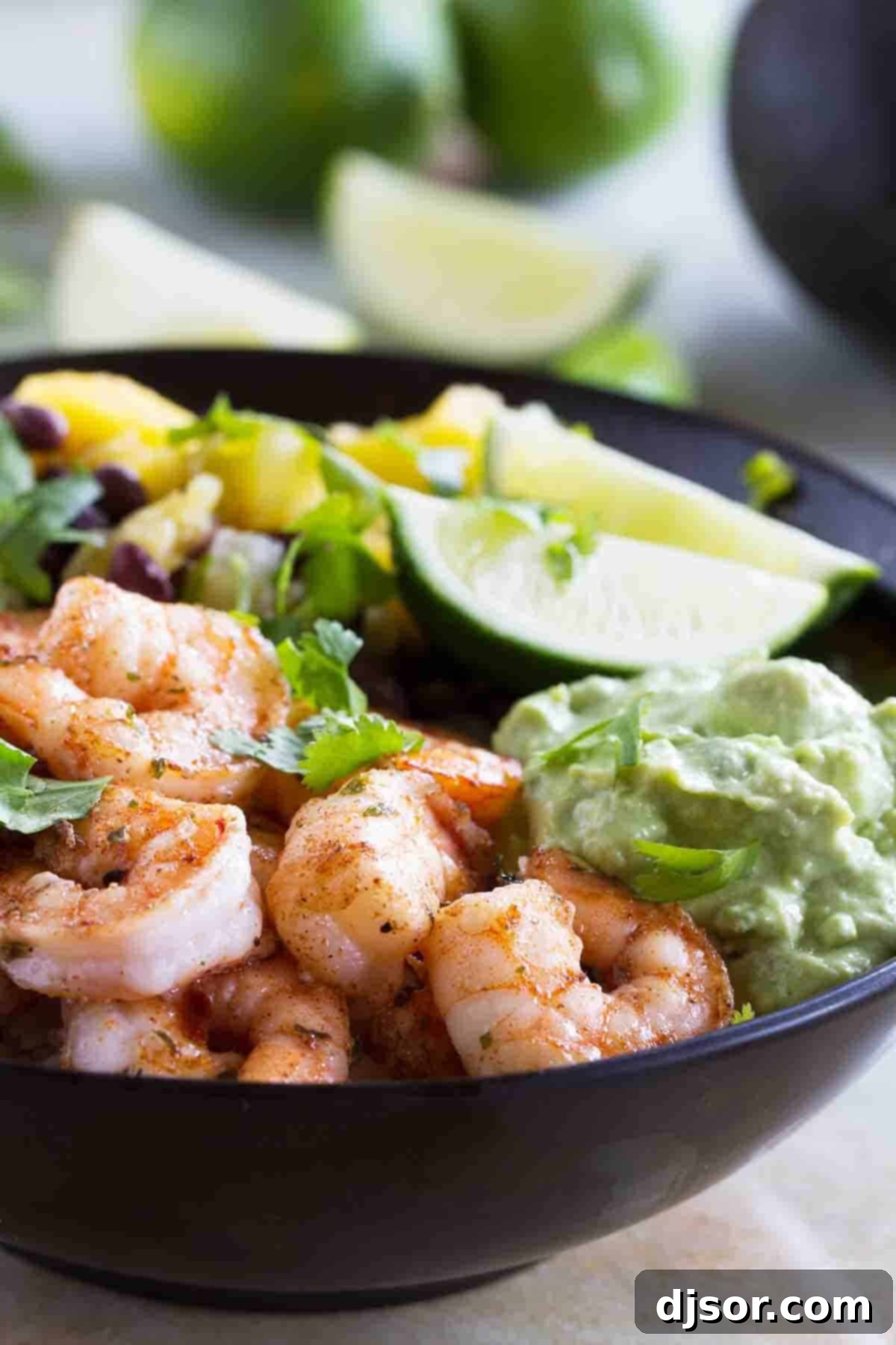 A close-up of a vibrant Spicy Shrimp Bowl, garnished with creamy avocado and fresh lime slices. Spicy Shrimp Bowl with avocado and lime slices.