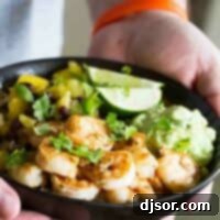 Spicy Shrimp Bowls: A vibrant and balanced meal. Hands holding a bowl filled with shrimp, rice, pineapple, mango, and avocado.