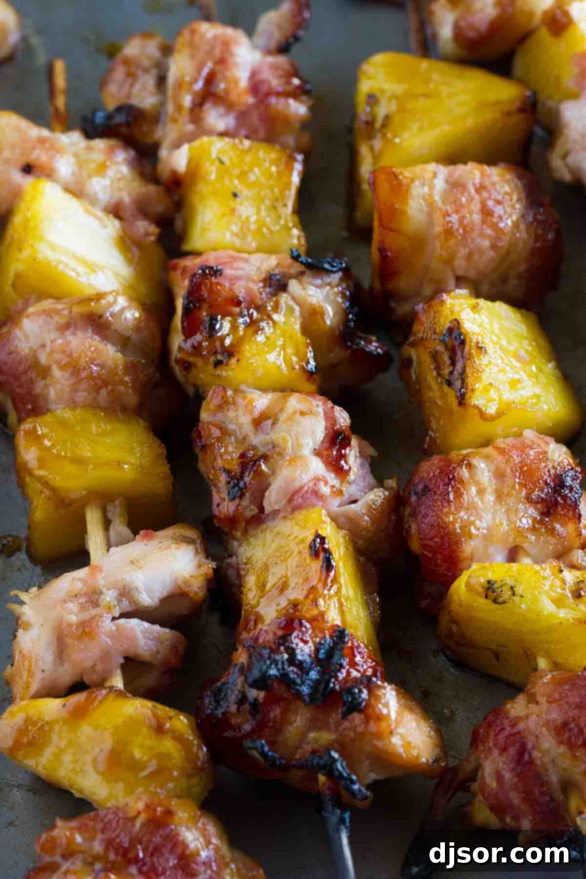Close-up shot of perfectly grilled Bacon Wrapped Teriyaki Chicken Skewers, showcasing crispy bacon, caramelized pineapple, and tender chicken.