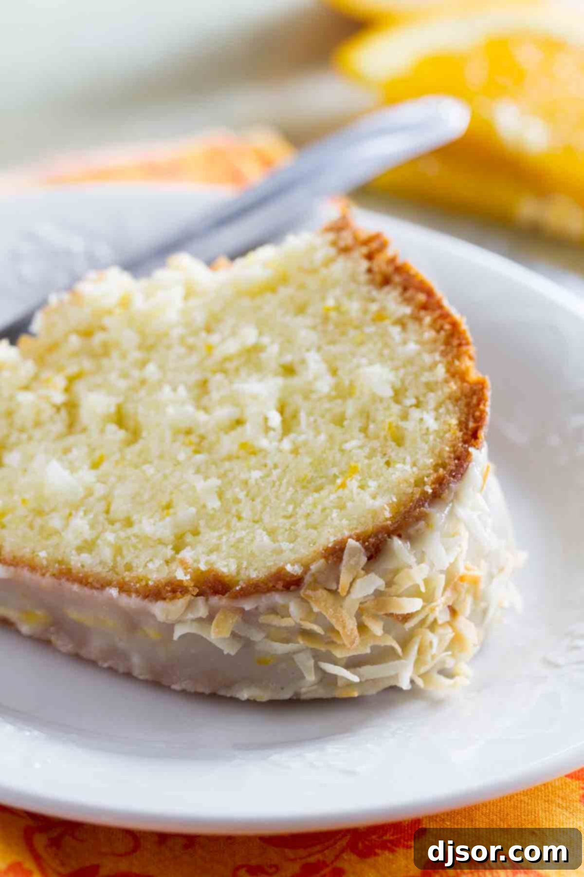 Slice of tropical Coconut Orange Pound Cake A delectable slice of Coconut Orange Pound Cake, moist and fluffy, served on a white plate, ready to be enjoyed.