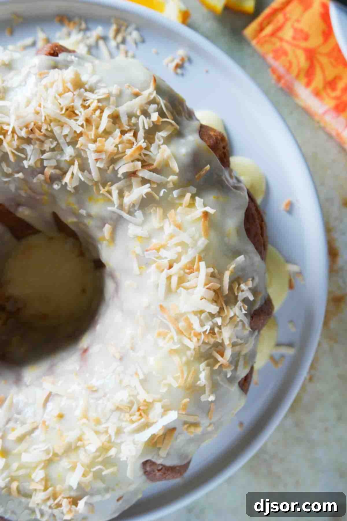Orange pound cake with icing and toasted coconut Close-up of a Coconut Orange Pound Cake generously topped with a sweet orange glaze and fragrant toasted coconut flakes.