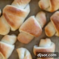 Classic Butterhorn Rolls Recipe Card Image Multiple butterhorn rolls on a sheet of parchment paper.