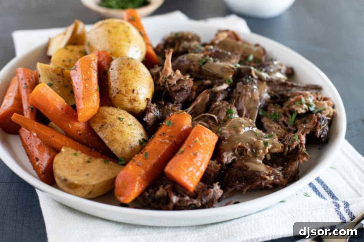 Sunday supper has never been so delicious! This Slow Cooker Pot Roast gives you perfectly tender beef, tasty (not mushy!) vegetables, and the most delicious gravy ever. Slow Cooker Pot Roast on a plate with carrots and potatoes