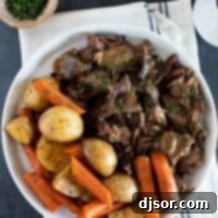 Melt-in-Your-Mouth Slow Cooker Pot Roast 7 Serving plate with chunks of pot roast with gravy and carrots and potatoes