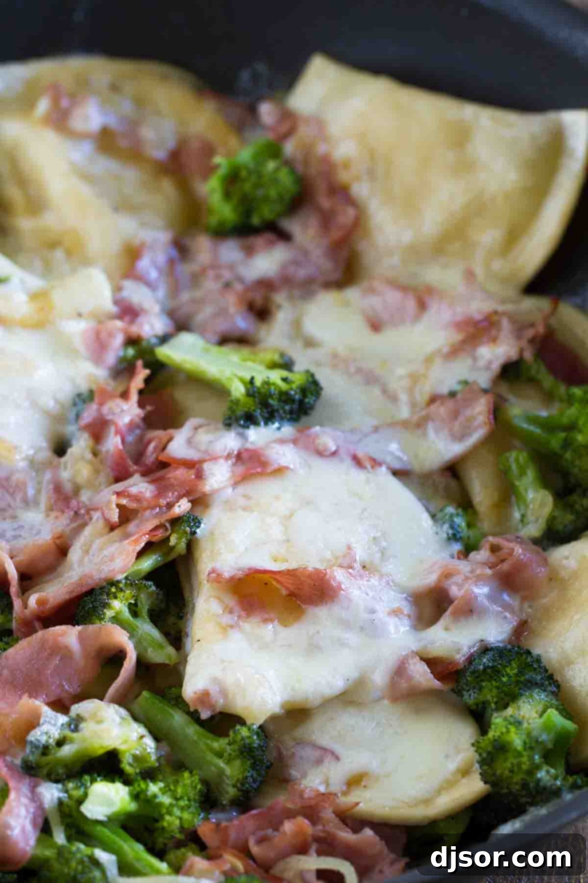 Skillet full of savory Pierogies with Ham and Broccoli, perfect for a quick dinner. A close-up view of cheesy pierogies, ham, and broccoli simmering in a large skillet, ready to be served.