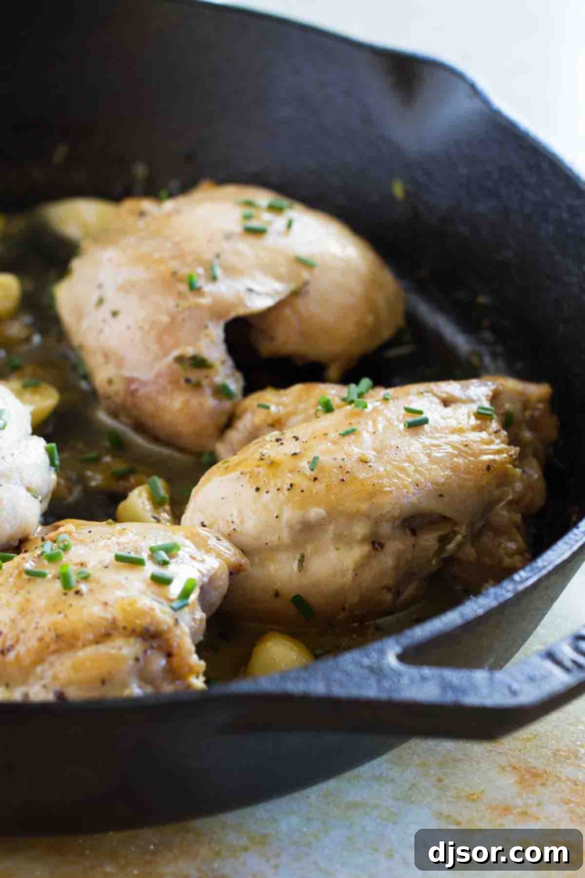 Skillet Chicken with Garlic and Herbs in a cast iron skillet, golden brown and garnished with fresh herbs.