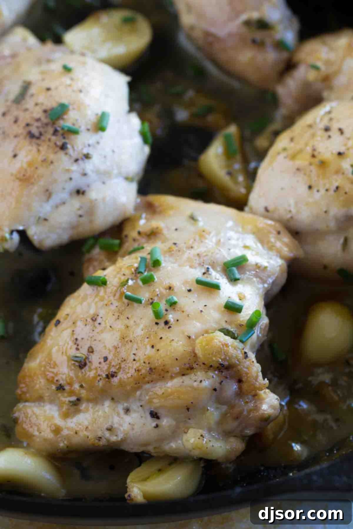 Succulent chicken thigh cooked in a cast iron skillet, garnished with fresh chives, ready to be served.