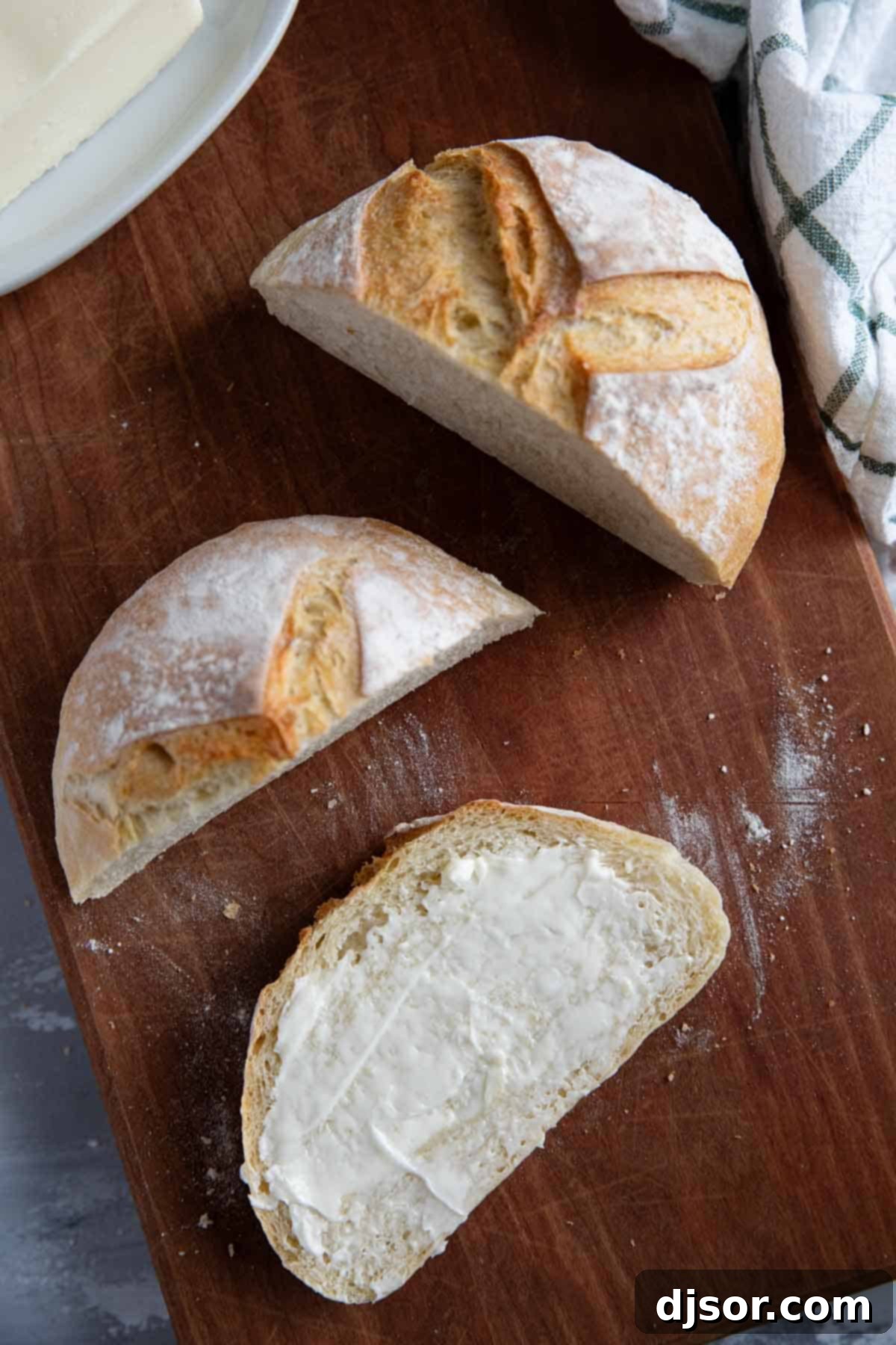 No Knead Crusty Artisan Bread 9 Loaf of artisan bread cut with butter spread on one slice.