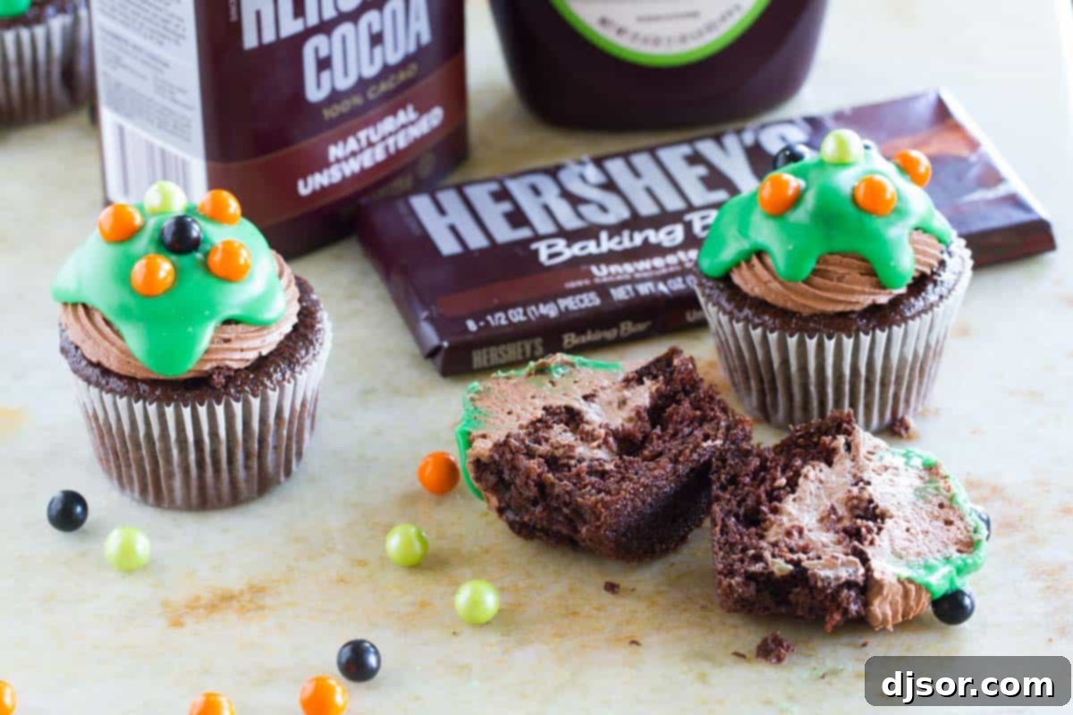 An Ultimate Chocolate Cupcake cut in half to reveal its rich chocolate mousse filling, topped with frosting and green ganache.