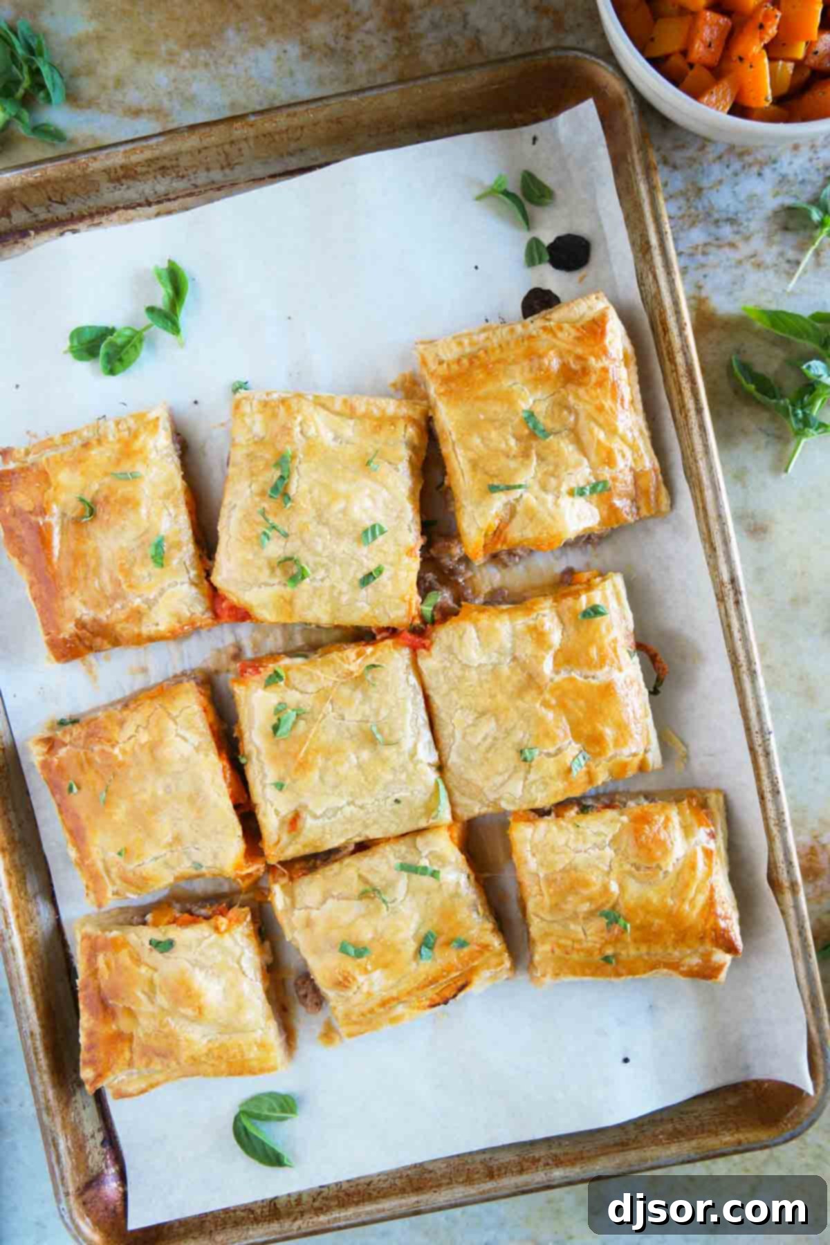 Sausage and Butternut Squash Slab Pie sliced into perfect squares on a baking sheet, ready to be served.