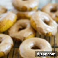 Baked pumpkin donuts stacked on a cooling rack.