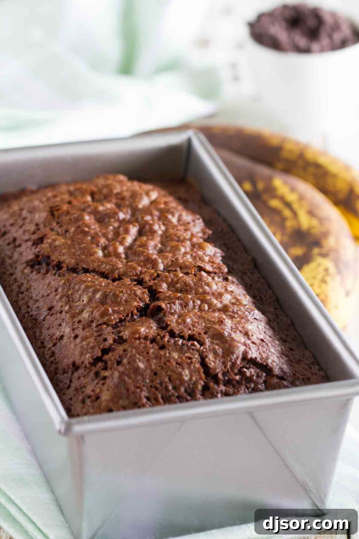 A warm loaf of Brownie Mix Banana Bread nestled in a baking pan, fresh from the oven.