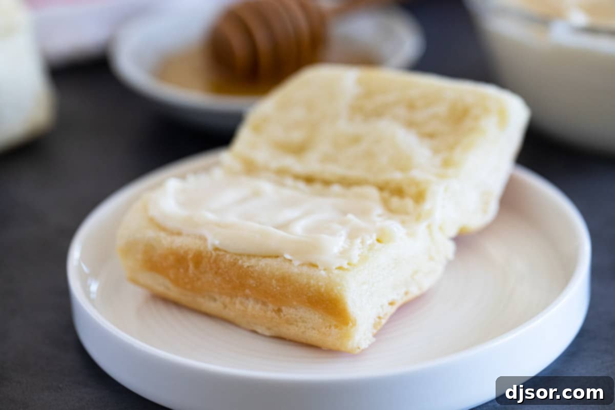 Perfect for slathering on homemade biscuits or rolls, this Honey Butter is going to be something that you always want in your refrigerator. Homemade roll with honey butter spread on half.