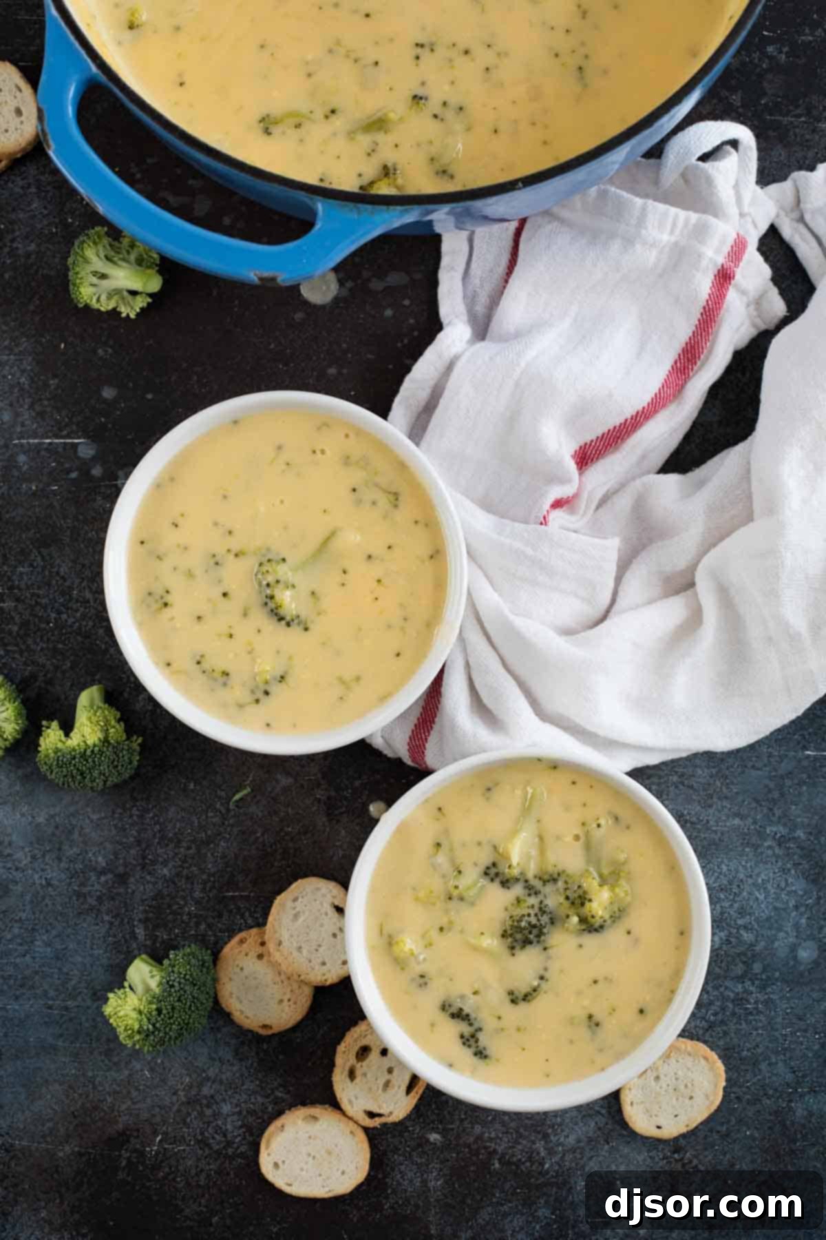 Overhead view of two bowls of creamy Broccoli Cheese Soup, garnished and ready for a comforting meal.