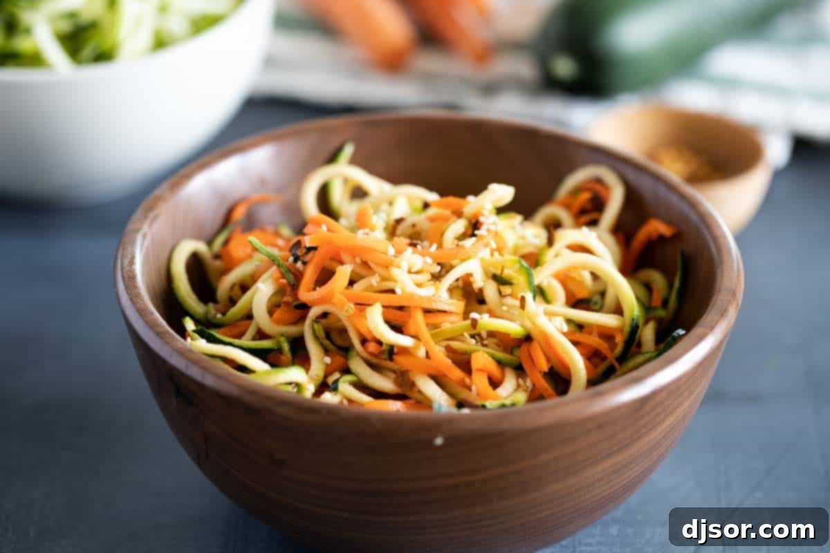 A vibrant bowl of Korean Cucumber Salad featuring spiralized cucumbers and carrots, garnished with sesame seeds.