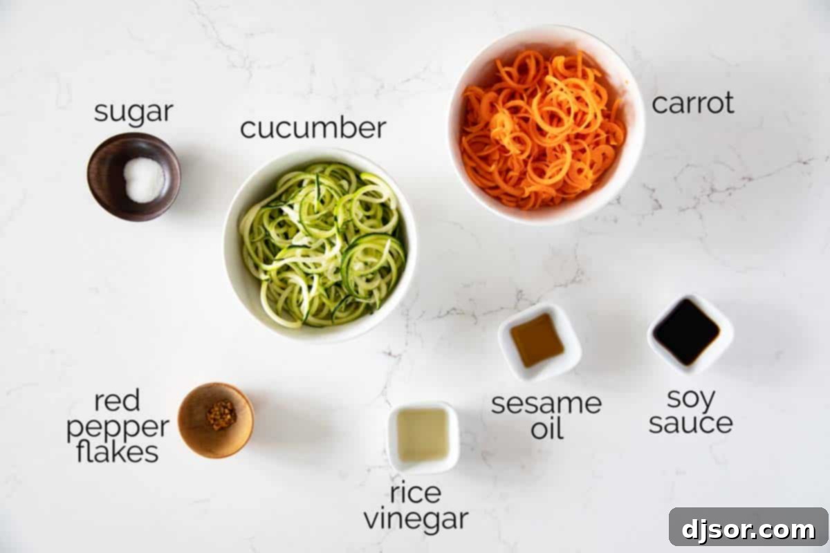 Arrangement of fresh ingredients including soy sauce, rice vinegar, sesame oil, sugar, red pepper flakes, cucumbers, and carrots, ready for making Korean Cucumber Salad.