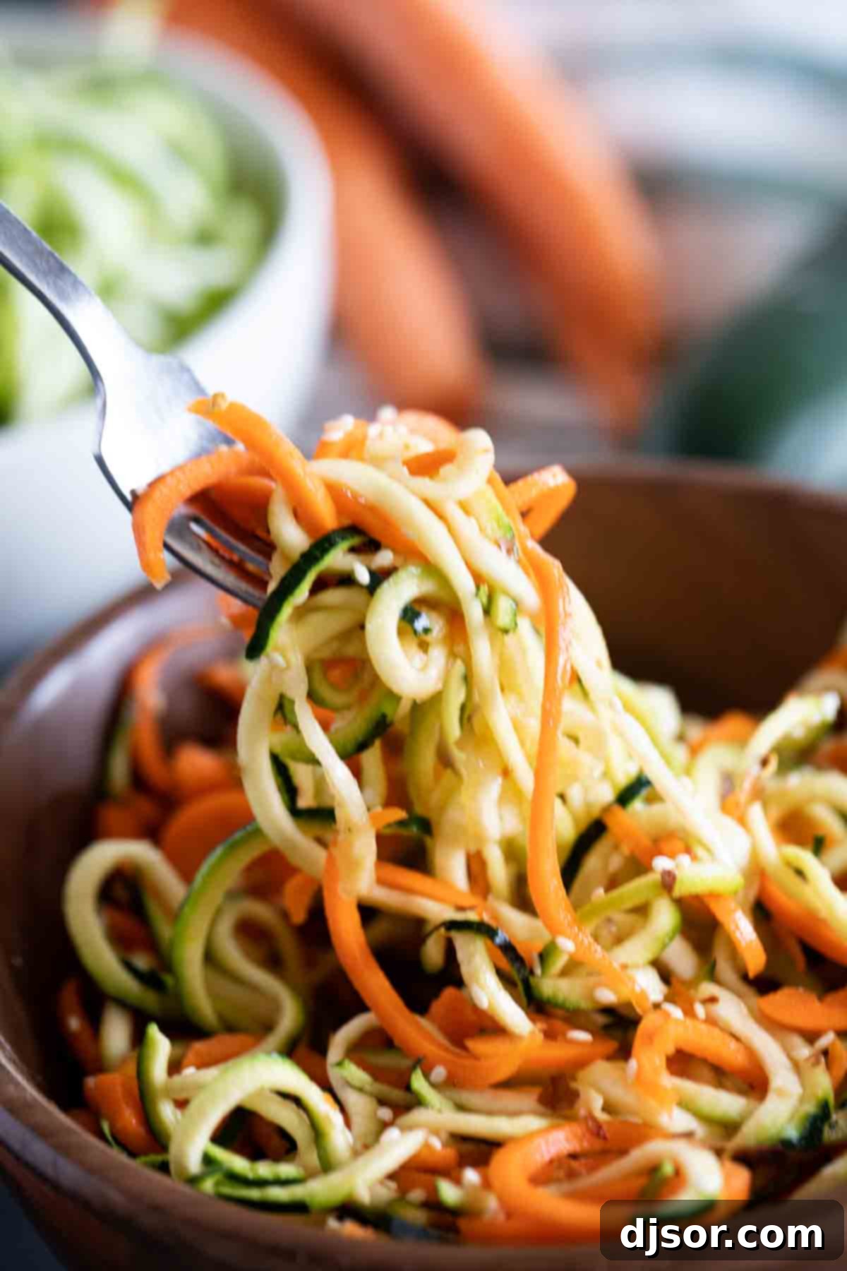 Close-up of a refreshing Korean Cucumber Salad, showcasing the intricate spiralized texture of cucumbers and carrots, garnished with sesame seeds, served as a vibrant side dish.