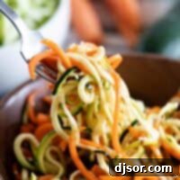 A vibrant bowl of Korean Cucumber Salad with spiralized cucumbers and carrots, ready to be served.